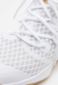 Biele športové tenisky z mesh materiálu s textúrovaným povrchom, vybavené bielymi šnúrkami a gumovou podrážkou, ktoré zdôrazňujú ventiláciu a ľahkú konštrukciu.