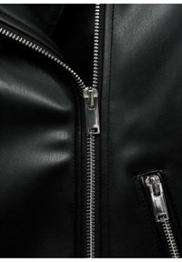 Giacca di pelle nera con cerniere argentate. Il dettaglio in primo piano mostra i denti della cerniera lucidi e la superficie in pelle testurizzata con tasche zip.