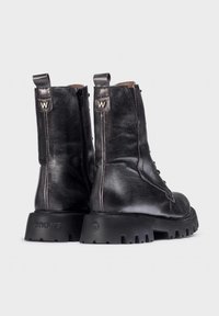 Botas negras de cuero hasta el tobillo con suela gruesa, diseño de cordones, cremalleras laterales y acentos de logo "W" en el tacón y la lengüeta.