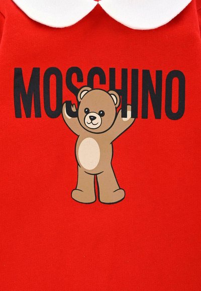 Rode katoenen kleding met een witte kraag, voorzien van een berenafbeelding en de tekst "MOSCHINO" in vetgedrukte zwarte letters. Soepele textuur.