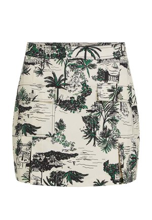 Jupe blanche avec un imprimé tropical détaillé en noir et vert, comprenant des palmiers et des paysages pittoresques. Comprend deux poches à l'avant.