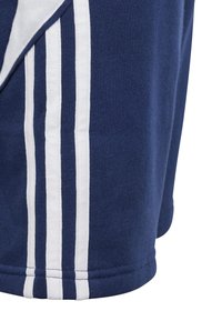Navy shorts made of cotton blend fabric with white vertical stripes and stitched hem details on the sides. Soft texture and athletic design.
