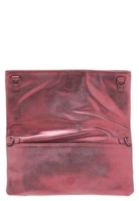 Červená metalická kabelka s hladkým povrchem, dvěma bočními uzávěry a přední kapsou. Interiér se zdá být mírně pomačkaný.
