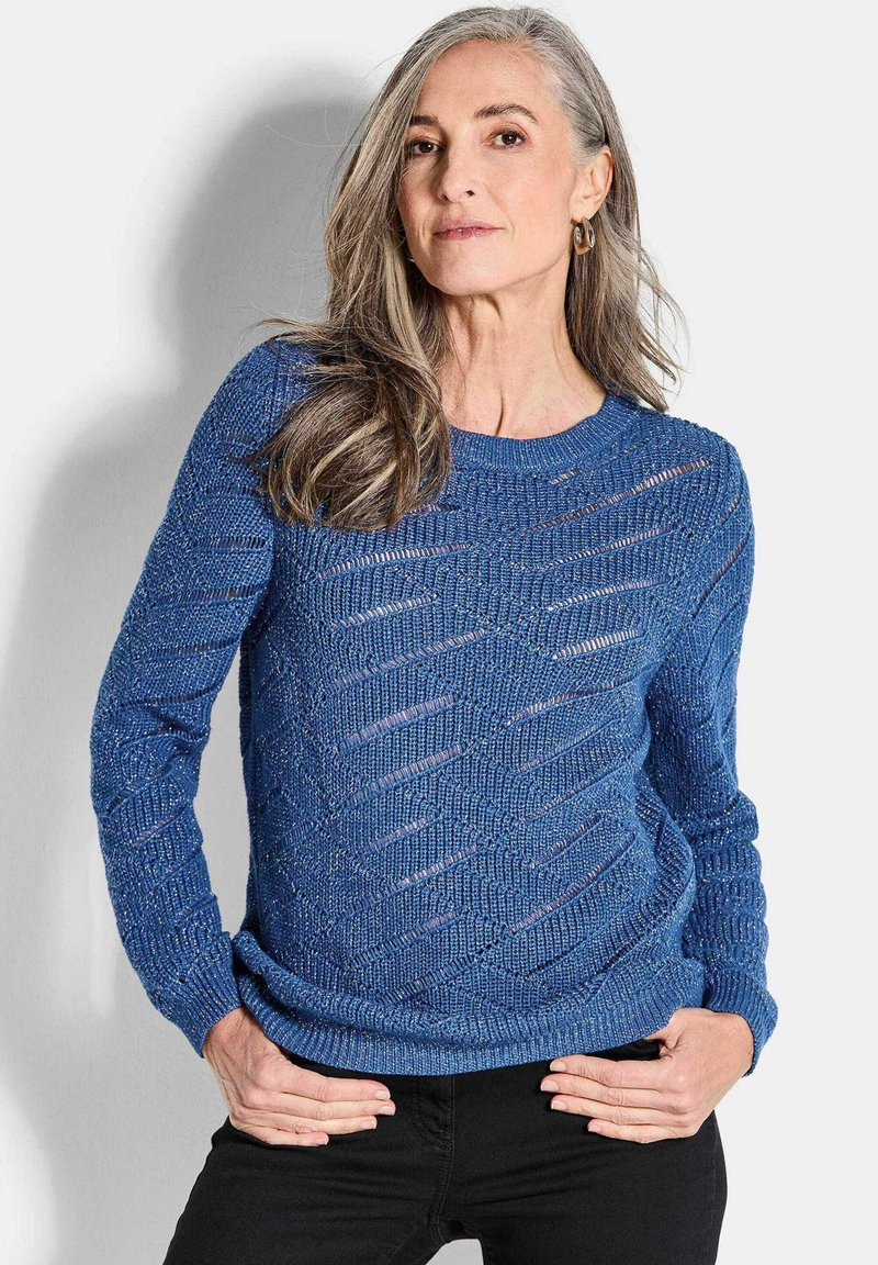 Blauer gestrickter Pullover mit strukturiertem Muster, der über Öffnungen verfügt und einen Rundhalsausschnitt hat. Lange Ärmel und lockerer Schnitt.