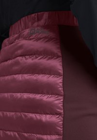 Gevoerde bordeauxrode jas met een glanzende afwerking en een horizontaal gestikt ontwerp, voorzien van een logo op de bovenste linkerkant en een gladde stoffen paneel.