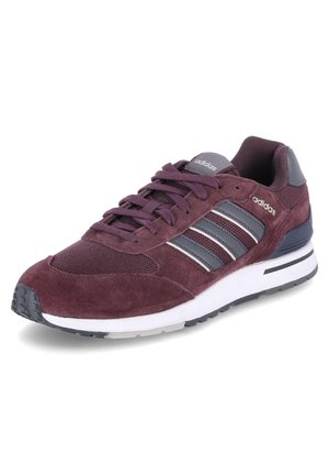 Viininpunainen Adidas-tennari, jossa samettinen ja verkkomainen päällinen, kolme harmaata raitaa, nauhakiinnitys ja valkoinen pehmustettu pohja, jossa mustat yksityiskohdat.