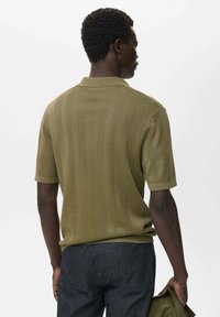 Olivgrünes Poloshirt mit kurzen Ärmeln und strukturiertem, geripptem Muster. Verfügt über einen klassischen Kragen und saubere Nähdetails.