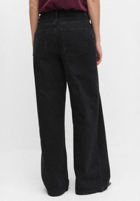 Szerokie spodnie dżinsowe w kolorze czarnym z teksturowanym wzorem w kropki, dwoma tylnymi kieszeniami i średnim stanem. Zaprojektowane z myślą o luźnym kroju.