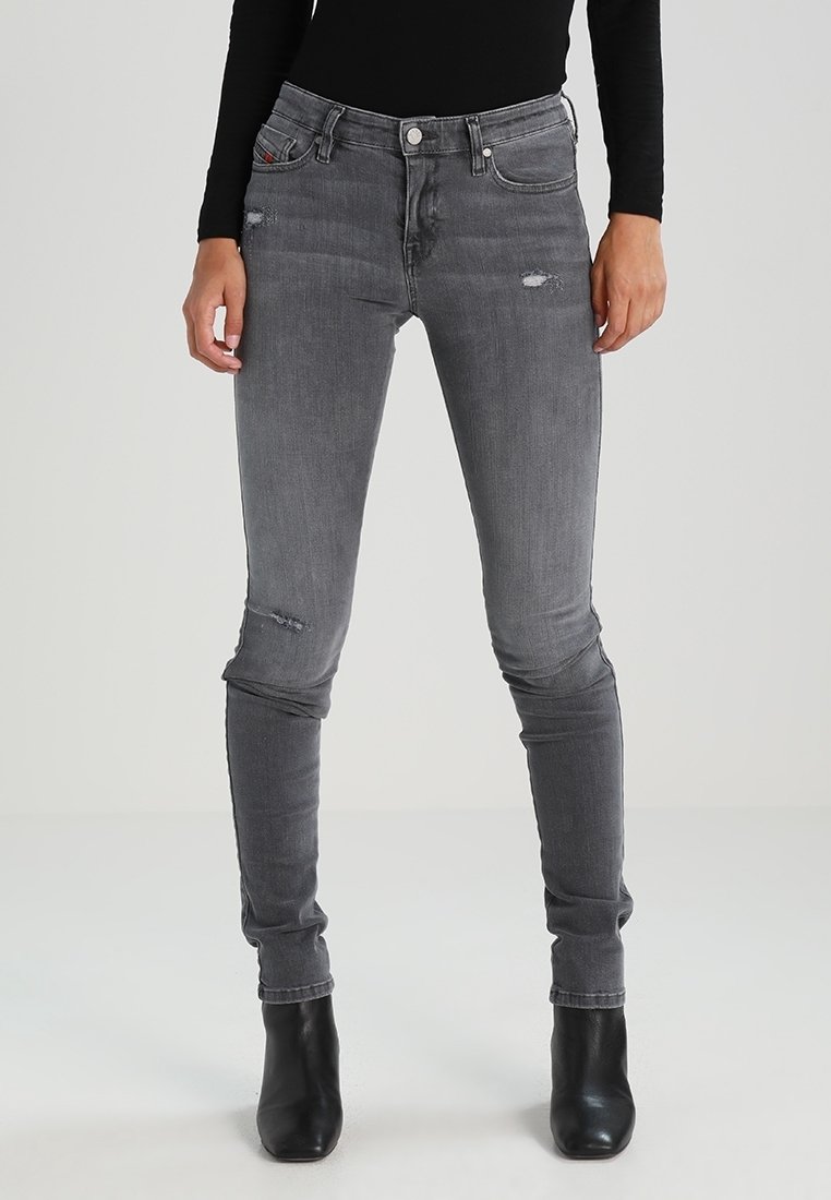 Jeans ajustados de mezclilla gris con detalles desgastados, con una cintura de altura media, cinco bolsillos y un diseño ceñido.