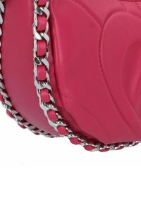 Borsa a mano in pelle di un vivace colore rosa, con tracolla a catena, texture liscia, forma arrotondata e dettagli in rilievo sulla superficie.