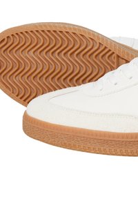 White sneakers with a textured suede toe, smooth leather body, and a gum rubber outsole featuring a wavy tread pattern.