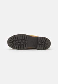 Talpa din cauciuc negru cu caneluri adânci, având un logo. Miezul este de culoare bej, cu o textură netedă, oferind amortizare și suport.