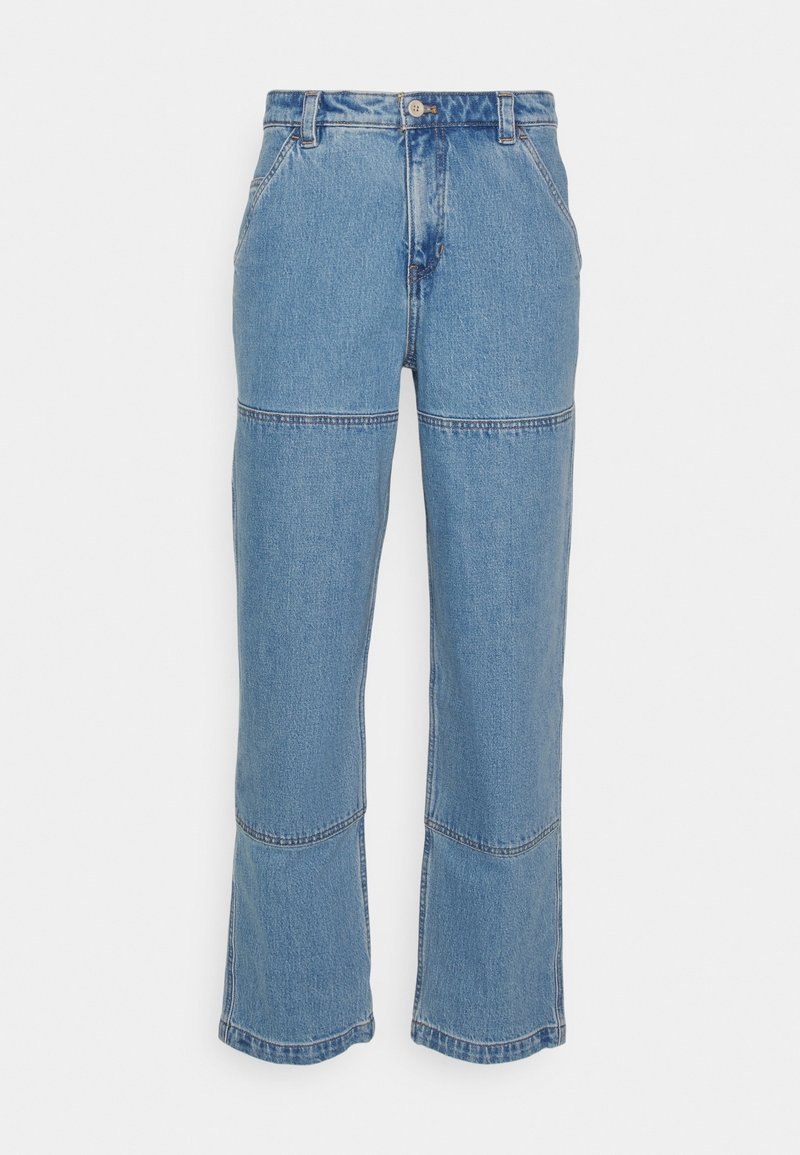 Jean droit en denim bleu avec des détails de coutures horizontales visibles sur les cuisses et les mollets, équipé de passants pour ceinture et d'une fermeture avant à boutons.