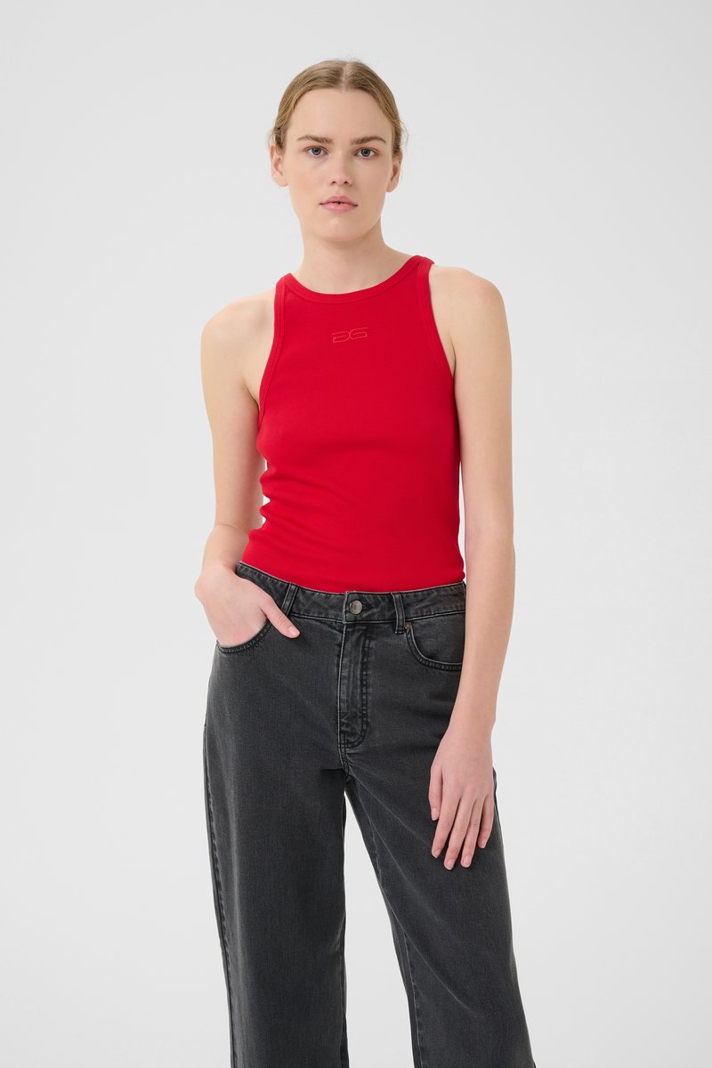 Débardeur rouge à côtes avec un col rond et un logo ; associé à un jean noir taille haute et coupe droite. Texture de tissu lisse.