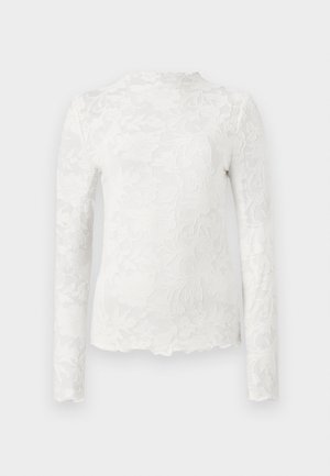 Hvit langermet topp med høy hals, med et subtilt blomstrete blondermønster og bølget kant.