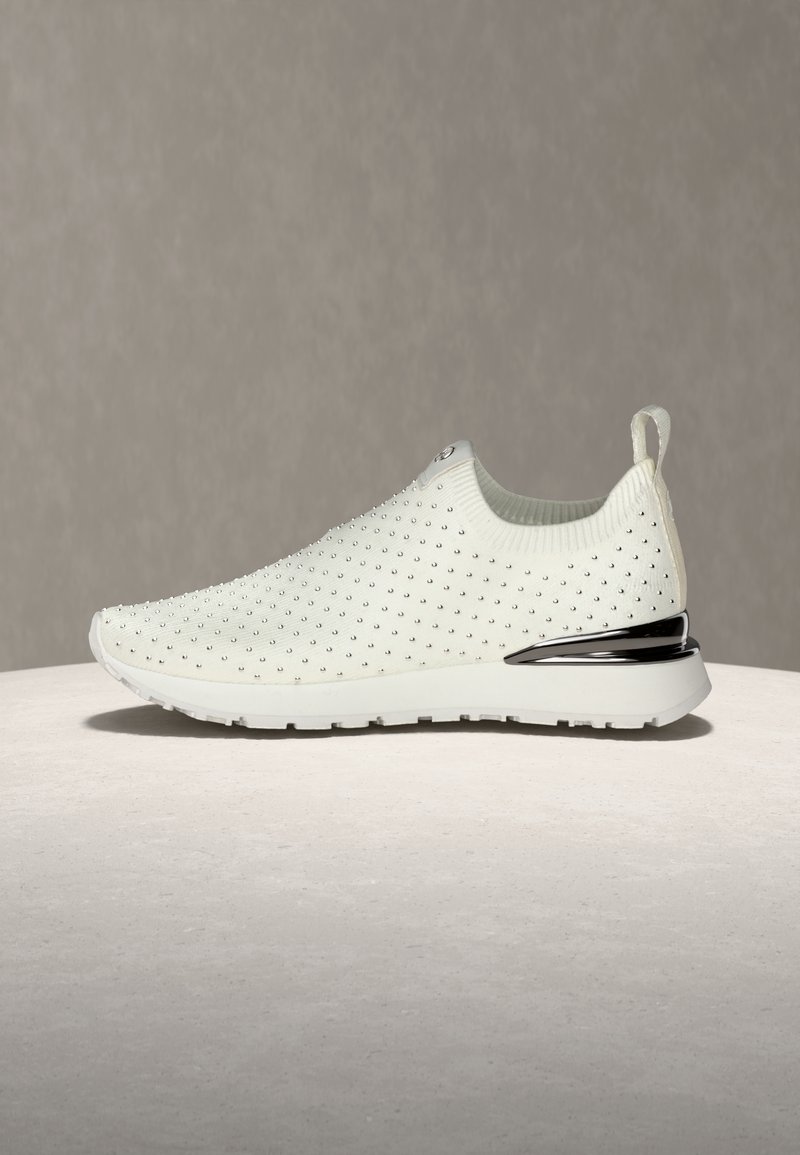 Sneaker à enfiler blanc avec une tige en tricot texturé ornée de petits clous métalliques. Comprend un accent métallique sur le talon et un col rembourré.