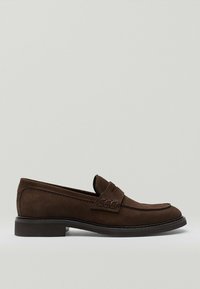Brune ruskind slip-on sko med en glat tekstur, rund tå, dekoreret strop og lav sort hæl. Sidesyn viser det enkle design.