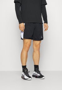 Zwarte sportshorts met witte zijaccenten, gemaakt van ademende stof. Combi met zwarte, witte en rode sportschoenen met een gestructureerd ontwerp.
