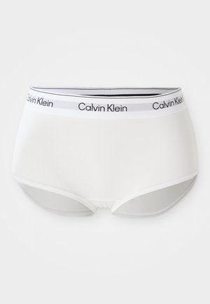 Hvide bomuldsunderbukser med en sort og grå elastisk talje. Har "Calvin Klein" logoet trykt på bæltet, glat tekstur, hipster stil.