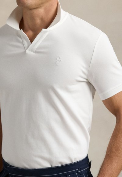 Balta trumpomis rankovėmis polo marškinėliai su apykakle ir siuvinėtu logotipu ant krūtinės. Lygus audinys ir prigludęs dizainas.