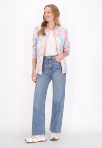 Giacca bomber colorata in tie-dye nei toni pastello di rosa, blu e giallo. Abbinata a jeans in denim a vita alta e sneakers bianche.