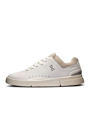 Baskets blanches avec un dessus en cuir lisse, des accents en mesh respirant et une semelle texturée, présentant des perforations subtiles et des détails de logo.