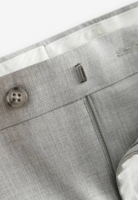 Harmaa kangashousut, joissa on napin suljenta, metallinen koukku ja vetoketju. Materiaalissa on hienovarainen tekstuuri ja sileä sisävuori.