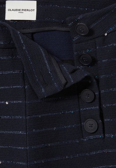 Tissu texturé marine avec des rayures horizontales et des sequins. Présente une fermeture à boutons avec quatre boutons noirs. L'étiquette indique "CLAUDIE PIERLOT, PARIS."