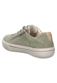 Zelené semišové tenisky s nízkým profilem, které mají boční zip, bílou gumovou podrážku a kontrastní hnědou patku.