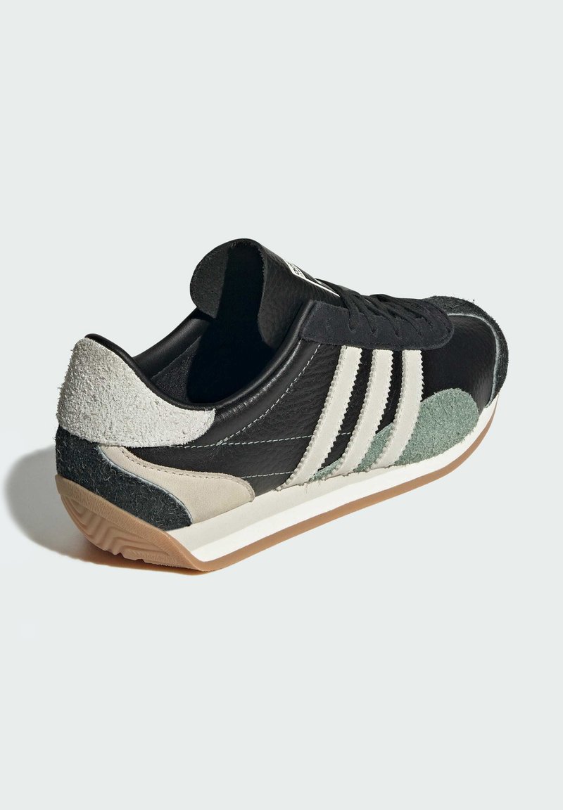 Czarne sneakersy wykonane z materiałów skórzanych i zamszowych, z trzema białymi paskami, teksturowanymi akcentami oraz gumową podeszwą.