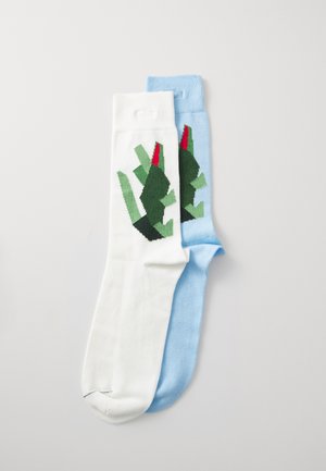 Cotton socks: one white with green and red graphic design; one light blue. Both feature smooth texture and ribbed cuff accents.