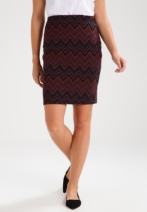 Jupe longueur genou avec un motif zigzag noir et rouge, fabriquée dans un tissu texturé. Conçue avec une silhouette ajustée et sans matériel visible.