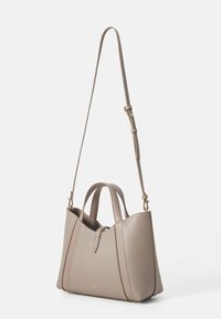 Beige Lederhandtasche mit zwei Obergriffen und einem abnehmbaren Schultergurt. Sie zeichnet sich durch eine strukturierte Form und dezente goldfarbene Markenelemente aus.