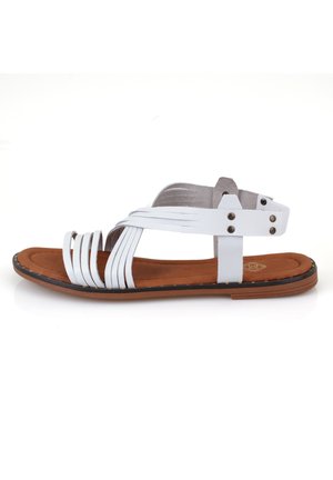 White sandal with multiple thin straps, brown cushioned insole, black rubber sole, and decorative silver hardware accents on the straps.