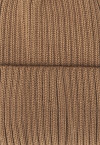 Bruine gebreide beanie met een gemeteoriseerd ribpatroon. Zachte, rekbare stof voor een comfortabele pasvorm. Heeft een opgerolde zoomdetail.