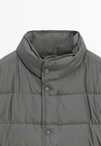 Graue Steppjacke mit hohem Kragen, ausgestattet mit einer gesteppten Textur, Druckknöpfen und einer glatten Stoffoberfläche.