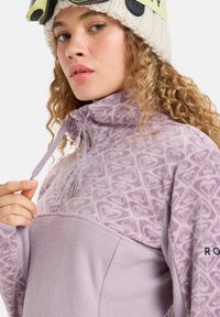 Helllila Fleece-Pullover mit geometrischem Muster, halbem Reißverschluss-Kragen und strukturiertem unteren Abschnitt. Verfügt über einen verstellbaren Kordelzug und Logo-Detail.