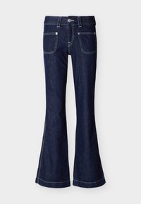 Σκούρο μπλε παντελόνι τζιν με φαρδιά πανσετάκια, μπροστινές τσέπες με μπαλώματα, αντίθετη λευκή ραφή, θηλιές για ζώνη και μεταλλικό κουμπί στη μέση.