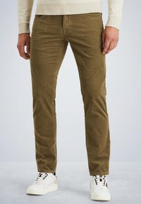 Pantaloni di velluto a coste verde oliva con taglio dritto, dotati di cinque tasche e una texture morbida, abbinati a sneakers bianche.