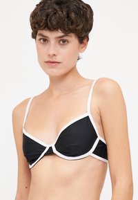 Fekete bikini felső fehér részletekkel; struktúrált dizájnnal, vékony állítható pántokkal és a kosárnál ráncolt anyaggal készült.