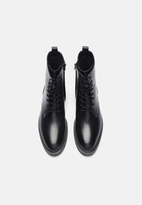 Botas de cuero negras hasta el tobillo con un acabado suave, con diseño de cordones, cremallera lateral y punta redonda. Adecuadas para ocasiones formales o informales.