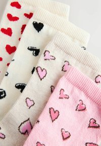 Patru perechi de șosete: inimioare roșii pe fond alb, inimioare negre pe fond crem, inimioare roz pe bej deschis și inimioare roz pe un fundal roz deschis.