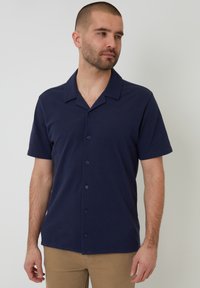 Koszula z krótkim rękawem, zapinana na guziki, w granatowym kolorze z gładkiego materiału, z kołnierzem typu spread i czarnymi guzikami. Minimalistyczny design.