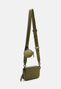 Borsa a tracolla verde oliva realizzata in materiale testurizzato, con un comparto principale rettangolare e un astuccio rotondo per monete attaccato alla tracolla.