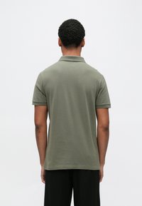 Polokošeľa v olivovo zelenej farbe, krátke rukávy, mäkká bavlnená látka, rebrovaný golier. Navrhnutá v klasickom strihu s jemnými líniami.