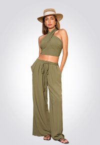 Conjunto de dos piezas en verde oliva, compuesto por un top corto con cuello halter y pantalones de pierna ancha. La tela es ligera, de textura suave y con una cinturilla ajustable.