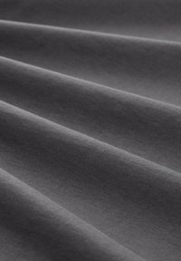 Dark gray fabric with a smooth texture, featuring soft folds and subtle sheen, reflecting light in varying shades across its surface.
