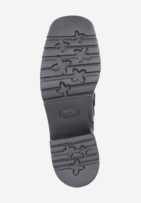 Schwarze Schuhsohle mit einem strukturierten Muster, das sternähnliche Formen und horizontale Rillen für besseren Halt aufweist. Kreisförmiges Logo in der Mitte.