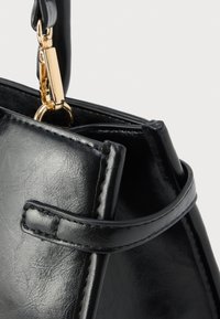 Μαύρη τσάντα χειρός από ψεύτικο δέρμα με δομημένο σχήμα, που διαθέτει επάνω λαβή και κούμπωμα με μεταλλικά στοιχεία σε χρυσή απόχρωση. Λεπτή υφή με ραμμένες λεπτομέρειες.