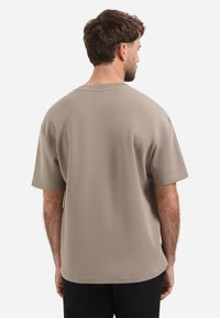 Beige katoenen t-shirt met een relaxed fit, korte mouwen en een ronde hals. Zichtbare naden en een label nabij de zoom.
